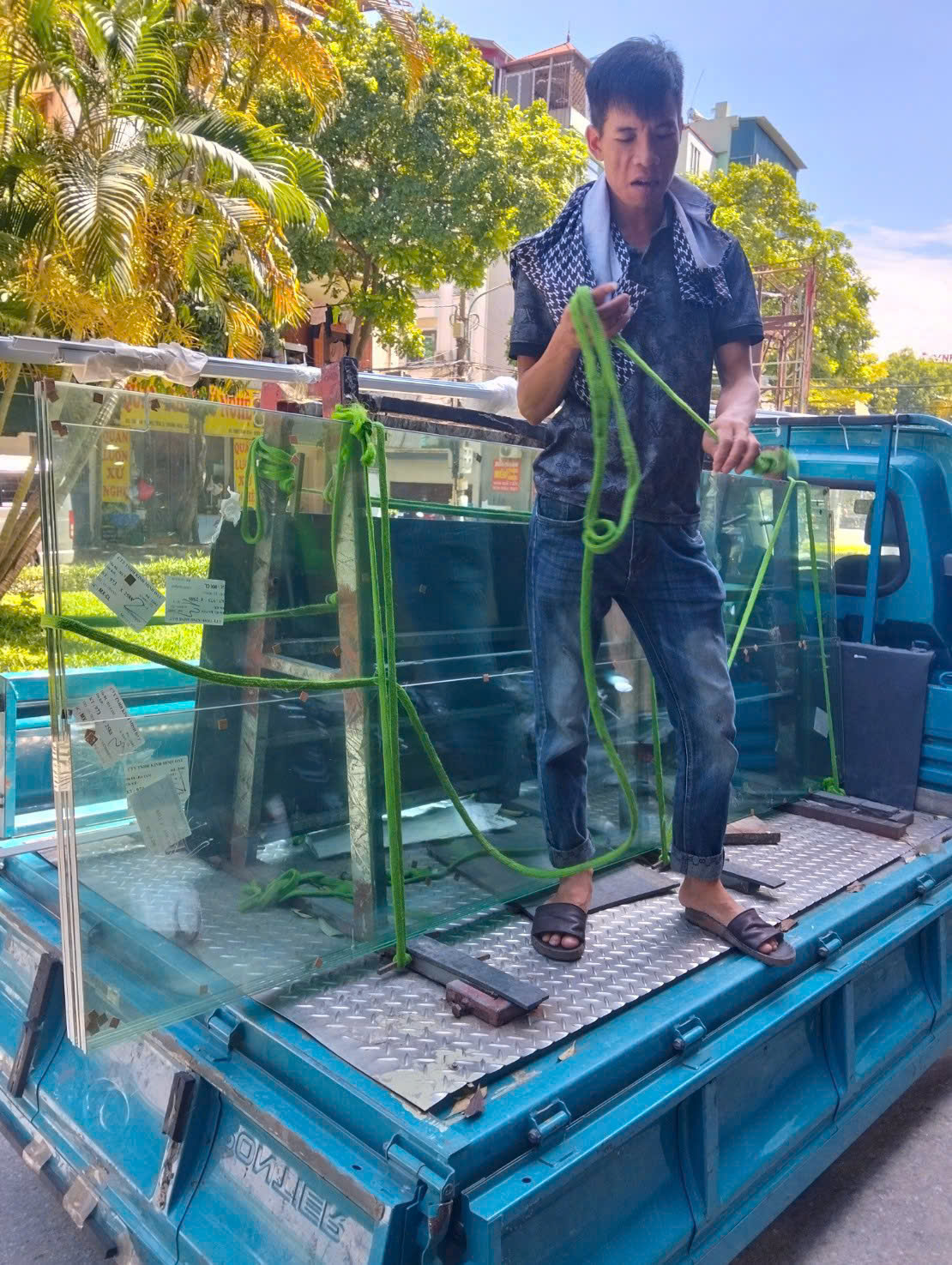 Nhân viên chuẩn bị dây nâng và cố định kính trên xe giao hàng